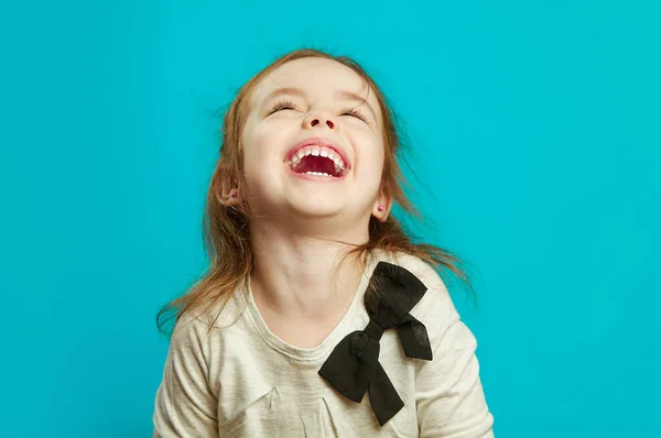 Радостная маленькая девочка смеется на синем фоне . — стоковое фото