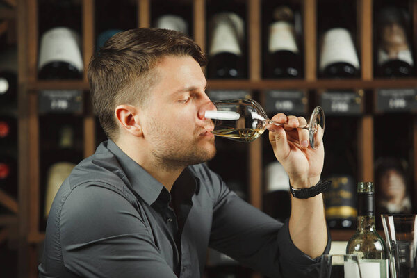 Сомелье дегустирует белое вино, выпивая его.
