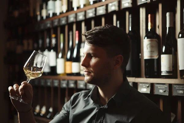 Beyaz şarap mahzende cam Sommelier bakar