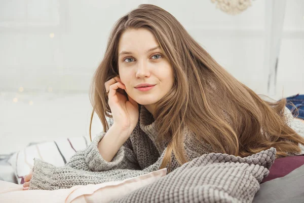 Beautiful woman no makeup lying on pillow in knitted sweater