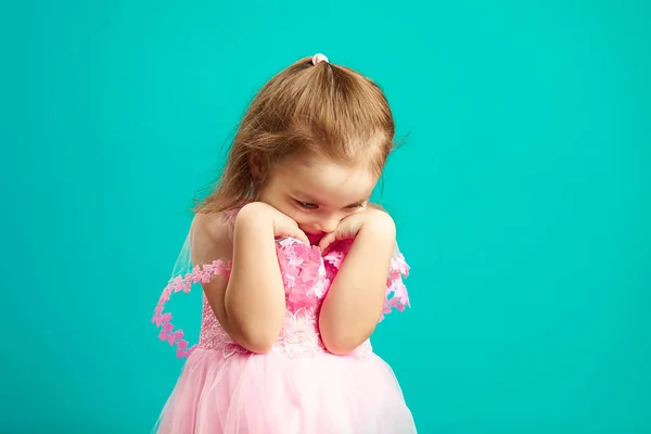 Offended little girl in pink dress on blue isolated.