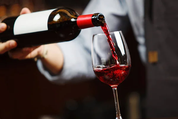 Garson şarap kadehine kırmızı şarap dolduruyor. Sommelier alkollü içecek doldurur.
