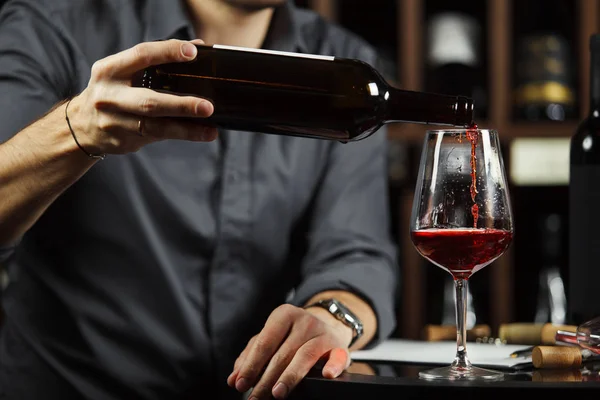Крупним планом знімок сомельє, що заливає червоне вино з пляшки в склянці — стокове фото