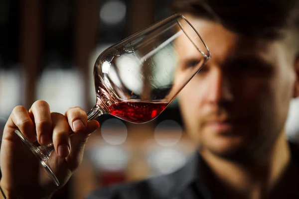 背景为红葡萄酒瓶，男性肉身鉴赏饮料 — 图库照片
