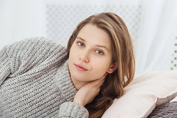 Beautiful woman no makeup lying on pillow in knitted sweater