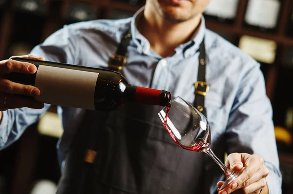 Male sommelier pouring red wine into long-stemmed wineglasses. — Stock Photo, Image