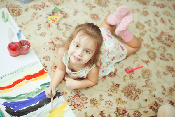 Ragazza sdraiata sul pavimento su tappeto con motivo floreale — Foto Stock