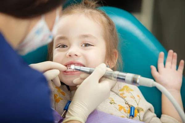 Dentist polishes childs teeth with modern electric tool