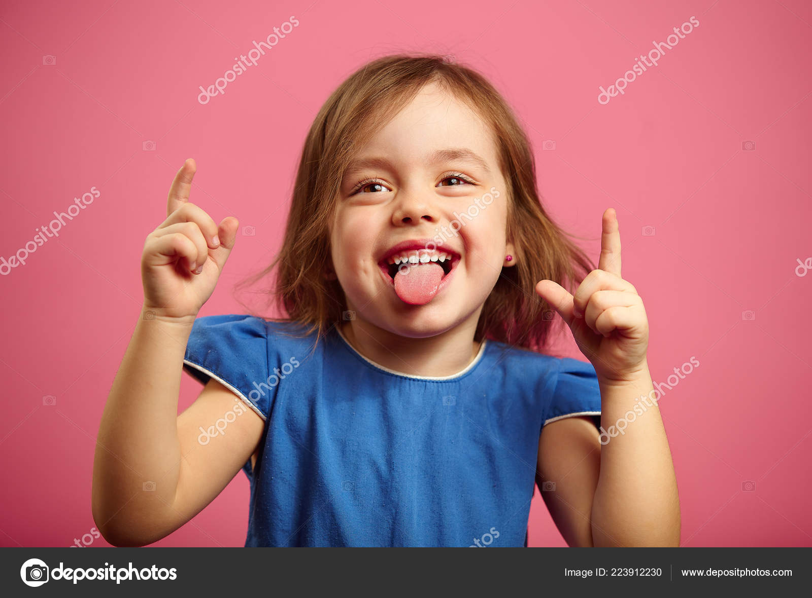 Cheerful little girl dancing with her hands raised and tongue sticking
