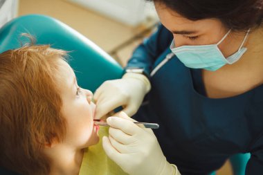 Dentist inserts cotton wool between the gums of child. Young patient with caries at a doctors appointment. Prevention of treatment for dental diseases. clipart