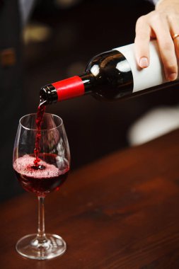 Garson şarap kadehine kırmızı şarap dolduruyor. Sommelier alkollü içecek doldurur.