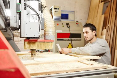 Adam CNC makinesini çizimle karşılaştırıyor. Sayısal denetimli aygıt.