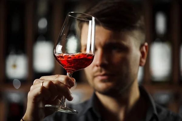 Bokal av rött vin på bakgrunden, manlig sommelier uppskattar dryck — Stockfoto