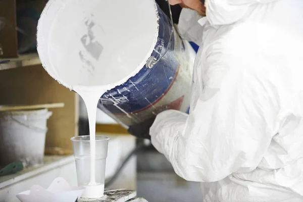 El hombre vierte la cantidad dosificada de pintura en una taza de plástico . — Foto de Stock