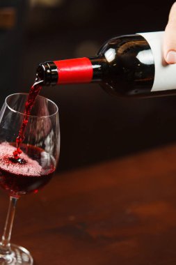 Garson şarap kadehine kırmızı şarap dolduruyor. Sommelier alkollü içecek doldurur.