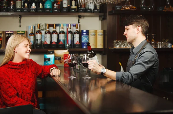 Bartender fills up two glasses with red wine from bottle