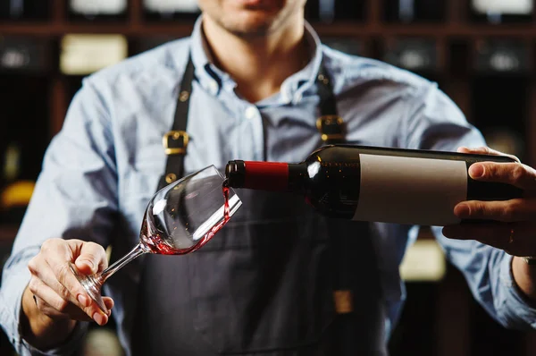 Sommelier masculino vertiendo vino tinto en las gafas de vino de tallo largo. — Foto de Stock