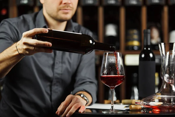 Крупним планом знімок сомельє, що заливає червоне вино з пляшки в склянці — стокове фото