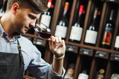 Arka planda bir şişe kırmızı şarap, erkek şarap garsonu içkinin değerini biliyor.