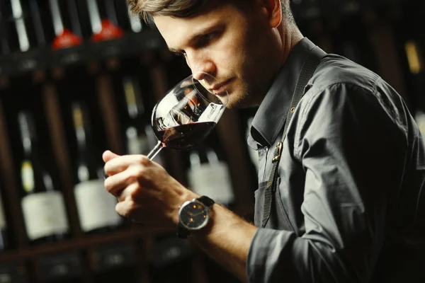 Бокал червоного вина на фоні, чоловічий сомельє цінує напій — стокове фото