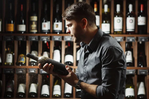 Sommelier segurando garrafa de vinho coberto com poeira — Fotografia de Stock