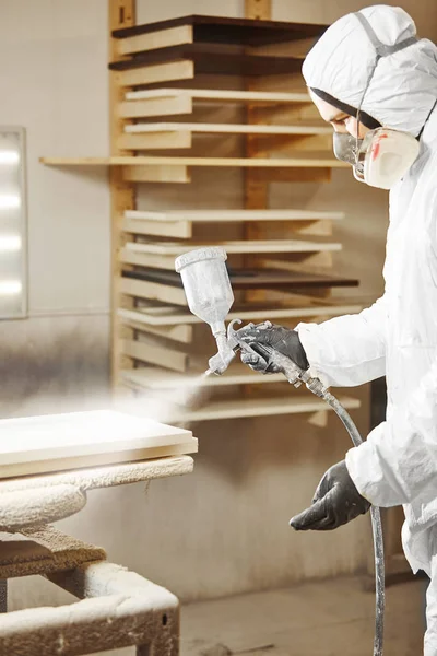 Hombre en respirador máscara pintura tablones de madera en el taller. —  Fotos de Stock