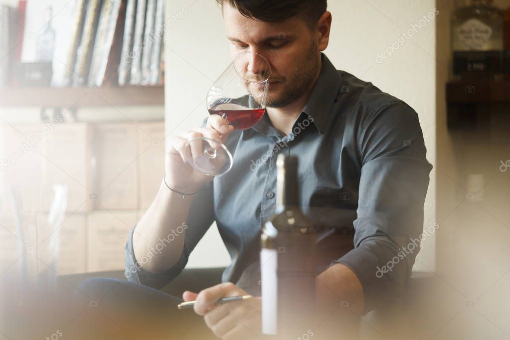 Person sitting and holding small glass of red wine