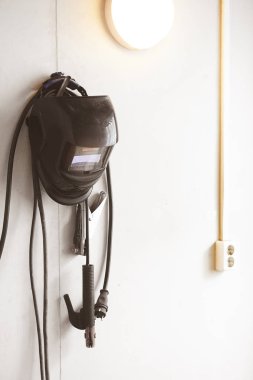 Beyaz bir arka plan üzerinde duvarda asılı kitle ile kaynak maskesi ve elektrikli kalem.