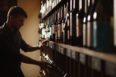 Şişelerden birine ahşap bodrumdan alarak sommelier