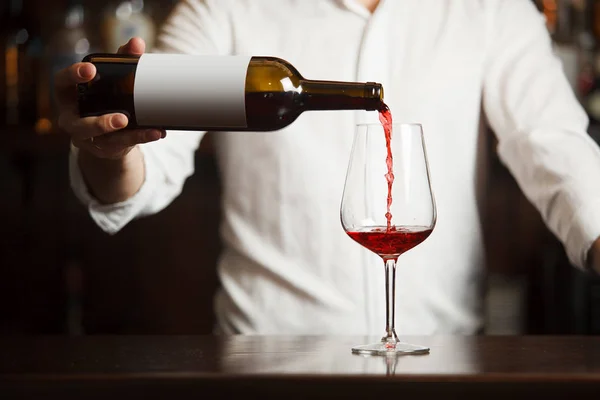 Férfi sommelier vörösbort öntve hosszú szárú borosüvegekbe. — Stock Fotó