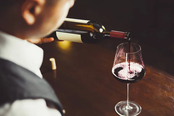 Närbild skott av sommelier hälla rött vin från flaska i glas — Stockfoto