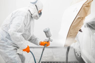 Adam aracın elementlerine beyaz boya püskürtür..