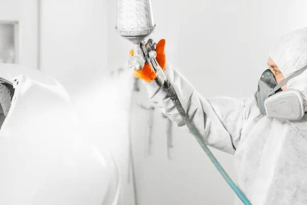 Spray painter worker in protective glove with airbrush pulverizer painting car body in white paint chamber. — Stock Photo, Image