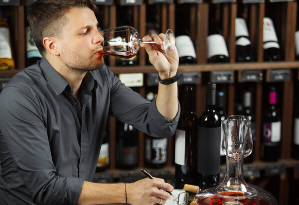 Сомелье дегустирует красное вино, выпивая его
