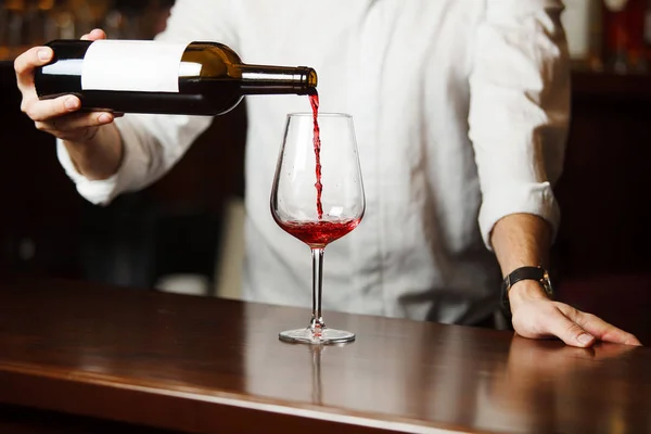 Чоловічий сомельє, що поливає червоне вино в довгоногі келихи винограду . — стокове фото