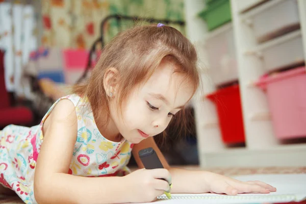 Mała dziewczynka dokładnie narysować obraz w notebooku z filcu pióra — Zdjęcie stockowe