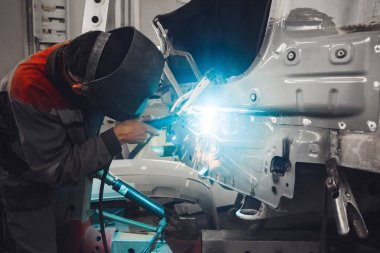 Karbondioksit kaynaklama makinesiyle çalışan metal araba gövdesi. Kazadan sonra tamir edilecek aracın tamiri.