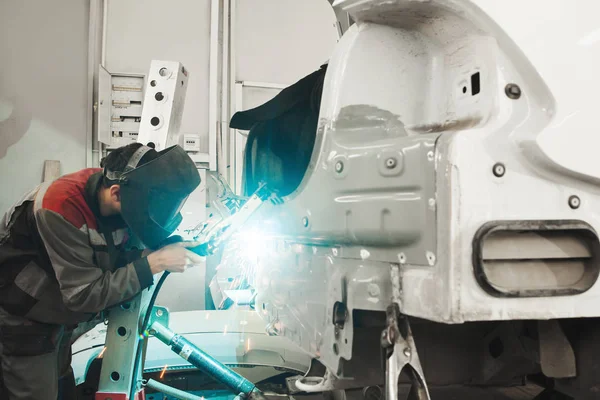 Industrial welder welds back bodywork of car. Weld of vehicle.