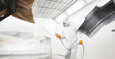 İşçiler arabaya beyaz boya püskürtüyor..