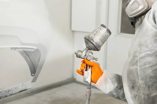 Trabajador masculino pintando un coche en una cabina de pintura blanca . — Foto de Stock