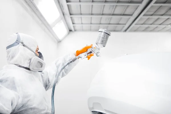 자동차 정비공 이 수리하는 동안 페인트 실에 스프레이 총을 가지고 흰색 자동차를칠 하는 모습. — 스톡 사진