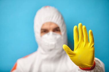 Tıp çalışanı, mavi izole bir arkaplanda dur işareti gösteriyor..