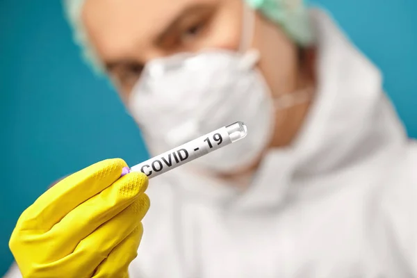 Express test on coronavirus. Scientist in protective coverall hold medical tube with test for a smear.