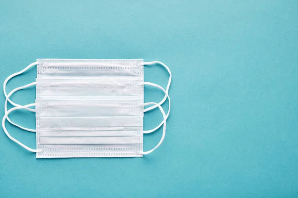 Primer plano de máscaras médicas sobre fondo azul, vista superior. Concepto de asistencia y apoyo médico mutuo . —  Fotos de Stock