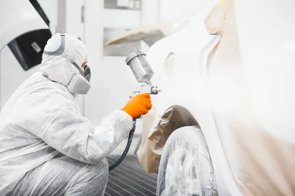 마스크를 쓴 자동차 수리공 과보호 작업을 하는 사람 페인트 칠 실에 흰색 자동차 몸을 그려 넣는 모습. — 스톡 사진