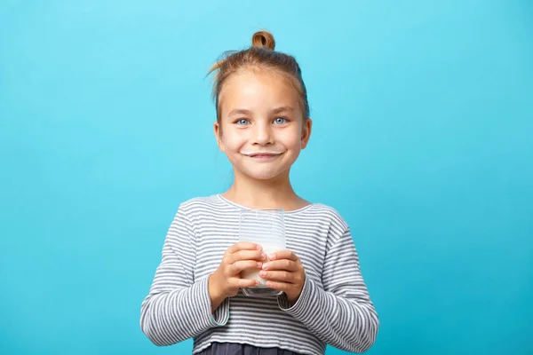 Petite fille mignonne avec verre de lait sur fond bleu isolé . — Photo