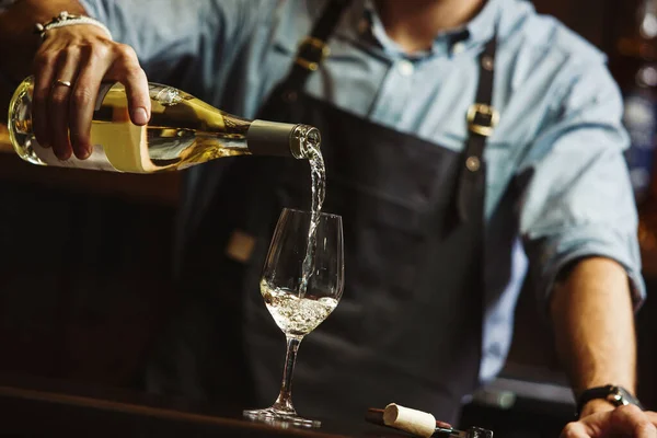 Férfi sommelier fehérbor özönlenek a hosszú szárú wineglasses. — Stock Fotó