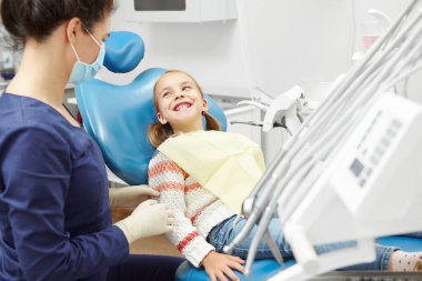 Gülümseyen genç hasta dişçiye bakar. Doktor muayenehanesindeki güzel kız..