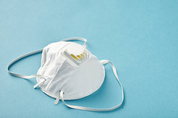Close up pharmacy respirator masks on blue background. Medical safety concept.