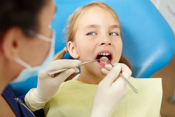 Dentista feminina examinando dentes de menina na clínica odontológica pediátrica . — Fotografia de Stock